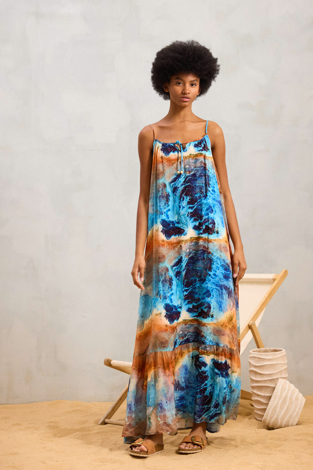 "SAPINE" maxi φόρεμα Namaste Μακρύ φόρεμα από 100% viscose, με λεπτές ρυθμιζόμενες τιράντες και στρογγυλή λαιμόκοψη, που διακοσμείται με κορδόνι στο ίδιο print και εχει ξύλινες χάντρες . Το τελείωμα της φούστας καταλήγει σε βολάν, ενισχύοντας τη ρευστότητα του σχεδίου. Το αφαιρετικό μοτίβο με υδάτινες μεταβάσεις δίνει βάθος και καλλιτεχνικό χαρακτήρα στο ρούχο. Σύνθεση : 100% Βισκόζη Τα ρούχα Namaste σχεδιάζονται και ράβονται στην Ελλάδα. Δωρεάν αποστολή σε 1-3 μέρες σε όλη την Ελλάδα. Διαθέσιμο και στο φυσικό κατάστημα YELLOW BUTTON Χρεμωνίδου & Δαμάρεως 61 Παγκράτι