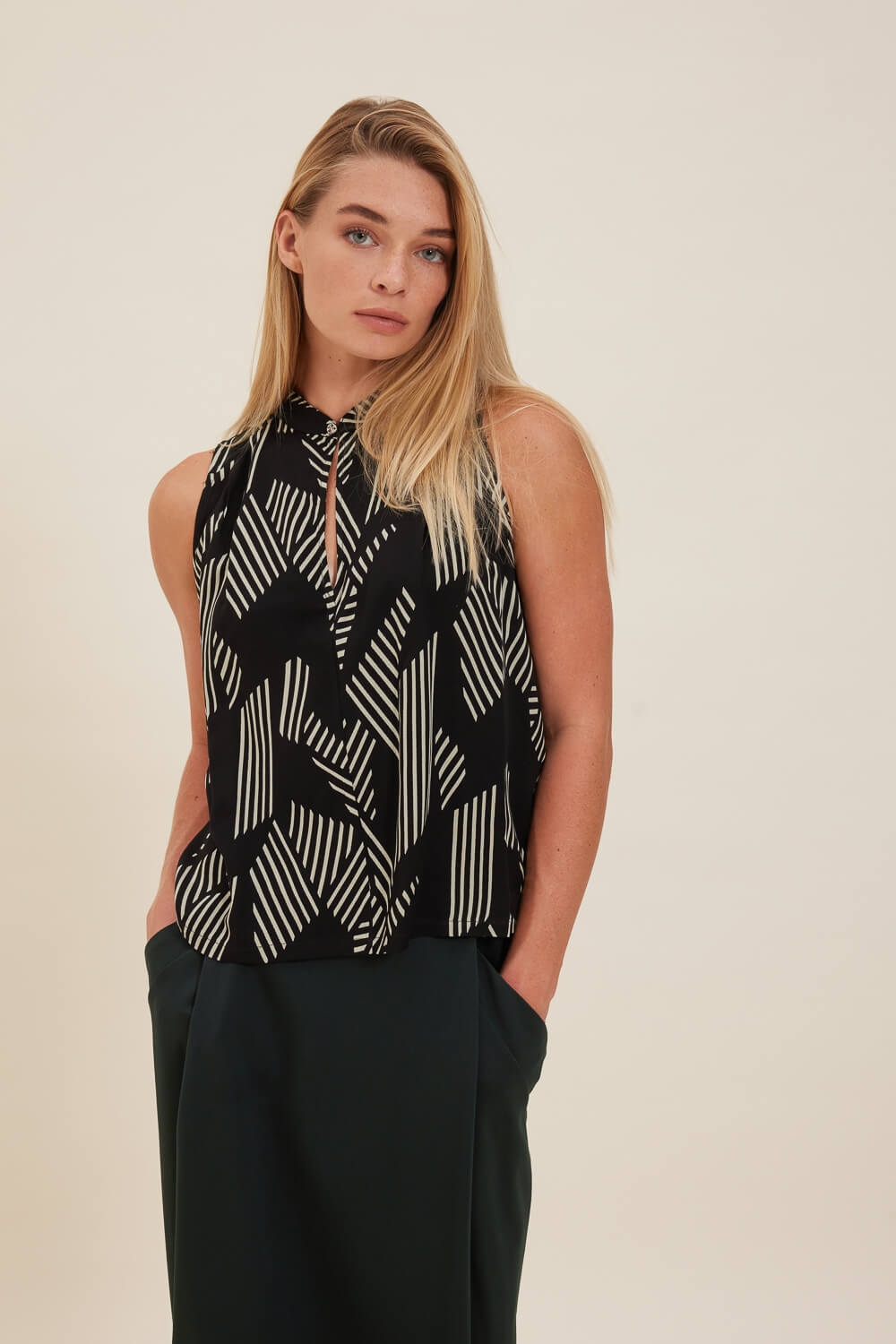 "LINNET" αμάνικο τοπ Namaste Αμάνικο τοπ σε χαλαρή γραμμή με μάο γιακά, που κουμπώνει με ένα μεταλλικό κουμπί, πιέτες στα πλαϊνά μπροστά λίγο πιο κάτω από τους ώμους, και μικρό άνοιγμα στις πλαϊνές. Τοπ από βισκόζη με γεωμετρικό print σε μαύρο και μπεζ χρώμα. 100% Βισκόζη Τα ρούχα Namaste σχεδιάζονται και ράβονται στην Ελλάδα. Δωρεάν αποστολή σε 1-3 μέρες σε όλη την Ελλάδα. Διαθέσιμο και στο outlet κατάστημα YELLOW BUTTON Γρ. Αυξεντίου 122 Ιλίσια