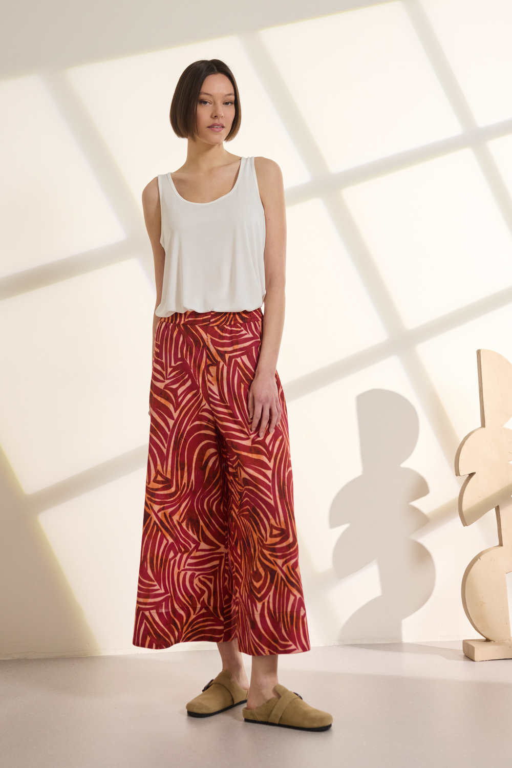 Παντελόνι Zip culotte από βαμβακερό ύφασμα με ιδιαίτερο all-over αφηρημένο print που προσδίδει δυναμικό σχεδιαστικό χαρακτήρα. Διαθέτει λάστιχο στη μέση για άνετη εφαρμογή, τσέπες και cropped μήκος με φαρδύ στρίφωμα στο κάτω μέρος. Συνδυάζεται ιδανικά με το πουκάμισο THIRZA_1, από το ίδιο ύφασμα, για ένα ολοκληρωμένο και εντυπωσιακό σύνολο. “Αυτό το προϊόν έχει φτιαχτεί με αγάπη και σεβασμό στο περιβάλλον χρησιμοποιώντας φυσικές ίνες.” 100% Βαμβάκι Το μοντέλο φοράει μέγεθος S. Τα ρούχα Namaste σχεδιάζονται και ράβονται στην Ελλάδα. Δωρεάν αποστολή σε 1-3 μέρες σε όλη την Ελλάδα. Διαθέσιμο και στα φυσικά καταστήματα YELLOW BUTTON Χρεμωνίδου & Δαμάρεως 61 Παγκράτι