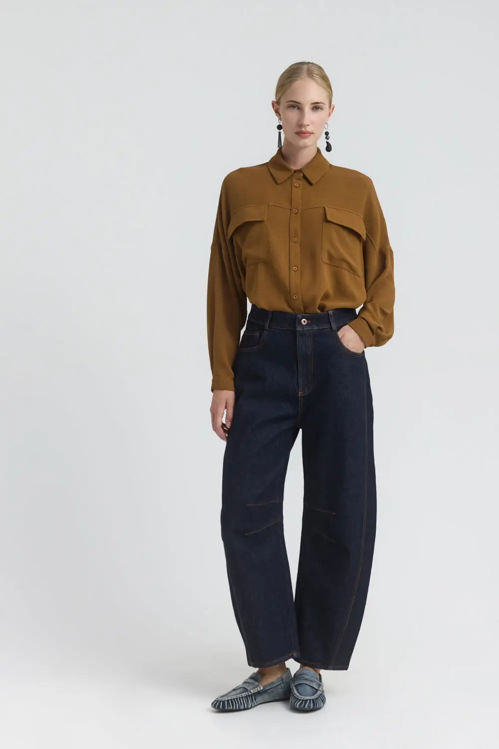Παντελόνι τζιν barrel σε mid waist γραμμή και χαμηλό καβάλο. Διαθέτει πεντάτσεπο σχεδιασμό και γαζιά σε χρωματική αντίθεση, προσδίδοντας μοντέρνα ταυτότητα στο denim look. Τα θυλάκια επιτρέπουν την προσθήκη ζώνης, ενώ κλείνει με μεταλλικό κουμπί και φερμουάρ. 99% Βαμβάκι 1% Εα Το μοντέλο φοράει μέγεθος S. Τα ρούχα Namaste σχεδιάζονται και ράβονται στην Ελλάδα. Δωρεάν αποστολή σε 1-3 μέρες σε όλη την Ελλάδα. Διαθέσιμο και στο φυσικό κατάστημα YELLOW BUTTON Χρεμωνίδου & Δαμάρεως 61 Παγκράτι Γρ. Αυξεντίου 122 Ιλίσια