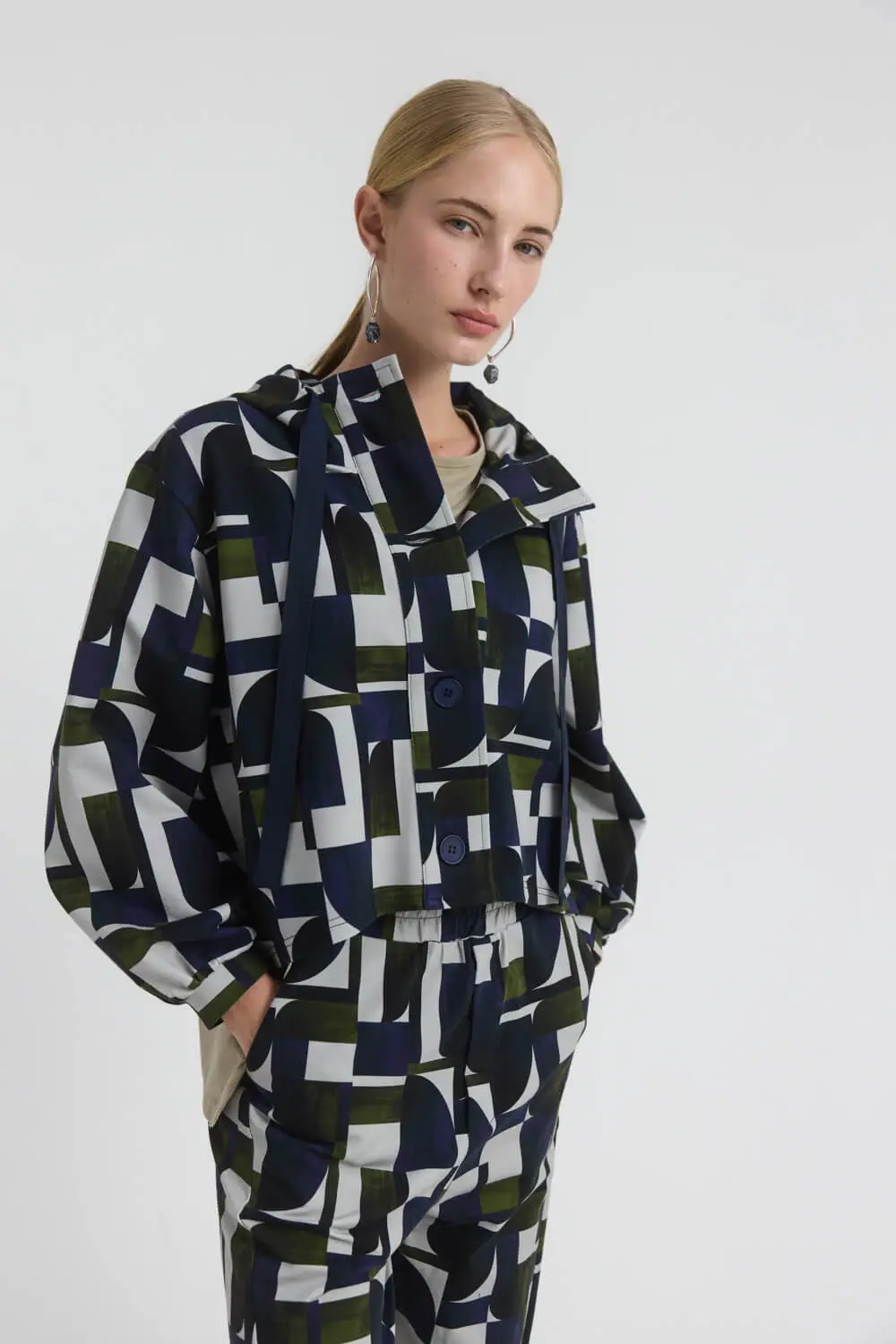 Ζακέτα cropped σε boxy γραμμή από ύφασμα cotton-lycra, με κουκούλα και γεωμετρικό print σε όλη την επιφάνεια. Διαθέτει μπροστινό κλείσιμο με κουμπιά και χαρακτηριστική πατιλέτα, ενώ τα μακριά μανίκια καταλήγουν σε μανσέτες. Τα πλαϊνά ανοίγματα δημιουργούν μια πιο ιδιαίτερη διαμόρφωση στο κάτω μέρος της γραμμής. Συνδυάζεται με το παντελόνι CLARKE από το ίδιο ύφασμα για τη δημιουργία σύγχρονου matching set. 95% Βαμβάκι 5% Λυοσέλ Τα ρούχα Namaste σχεδιάζονται και ράβονται στην Ελλάδα. Δωρεάν αποστολή σε 1-3 μέρες σε όλη την Ελλάδα. Διαθέσιμο και στο φυσικό κατάστημα YELLOW BUTTON Χρεμωνίδου & Δαμάρεως 61 Παγκράτι
