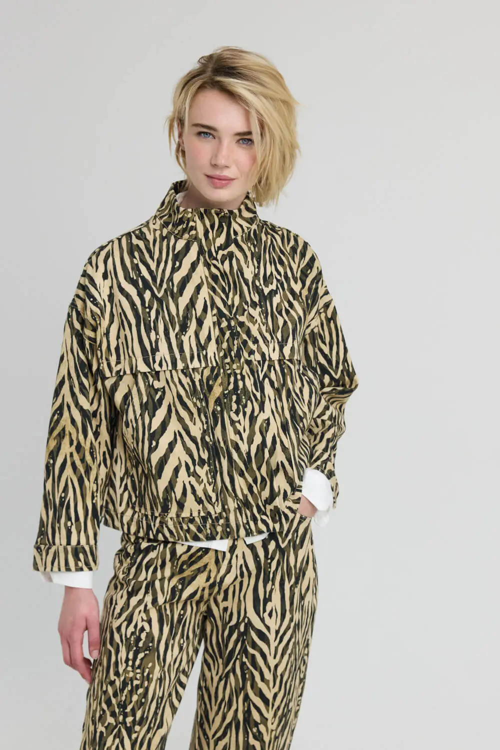 Τζάκετ σε άνετη, boxy γραμμή με zebra animal print και όρθιο γιακά. Διαθέτει χαμηλωμένους ώμους και μακριά μανίκια που καταλήγουν σε μανσέτες με κουμπί. Τα σχεδιαστικά κοψίματα στο επάνω μέρος τονίζουν τη χαρακτηριστική κατασκευή του, ενώ οι δύο μεγάλες patch pockets μπροστά διαθέτουν λοξό άνοιγμα. Κλείνει μπροστά με μεταλλικό φερμουάρ και κρυφή πατιλέτα, η οποία ασφαλίζει με κουμπιά στο επάνω και στο κάτω μέρος, ενώ διαθέτει και διακριτικά πλαϊνά ανοίγματα. Συνδυάζεται με το παντελόνι TOGA από το ίδιο ύφασμα για τη δημιουργία ολοκληρωμένου σετ. 100% Βαμβάκι Χαρακτηριστικά: Άνετη boxy γραμμή Zebra animal print Όρθιος γιακάς Χαμηλωμένοι ώμοι Μακριά μανίκια με μανσέτες και κουμπί Σχεδιαστικά κοψίματα στο επάνω μέρος Δύο μεγάλες patch pockets με λοξό άνοιγμα Μεταλλικό φερμουάρ μπροστά Κρυφή πατιλέτα με κουμπιά επάνω και κάτω Διακριτικά πλαϊνά ανοίγματα Οδηγίες πλυσίματος: Πλύσιμο στους 30°C. Χωρίς λευκαντικό και στεγνωτήριο. Σιδέρωμα σε χαμηλή θερμοκρασία. Δεν επιτρέπεται το στεγνό καθάρισμα. Διαστάσεις μοντέλου: Ύψος 1,78 m Στήθος 80 cm Μέση 61 cm Γοφοί 90 cm Τα ρούχα Namaste σχεδιάζονται και ράβονται στην Ελλάδα. Δωρεάν αποστολή σε 1-3 μέρες σε όλη την Ελλάδα. Διαθέσιμο και στο φυσικό κατάστημα YELLOW BUTTON Χρεμωνίδου & Δαμάρεως 61 Παγκράτι Γρ. Αυξεντίου 122 Ιλίσια